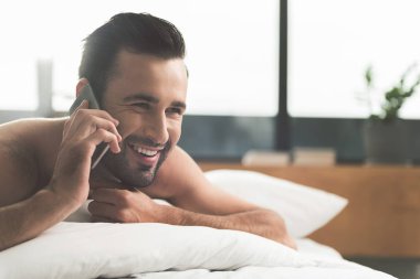 Neşeli genç adam tarafından yatak odasında cep telefonu konuşma