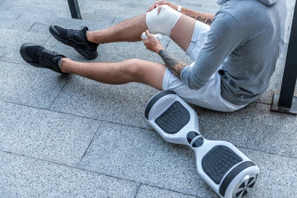 Man bandaging leg on floor outdoor — Stock Photo, Image