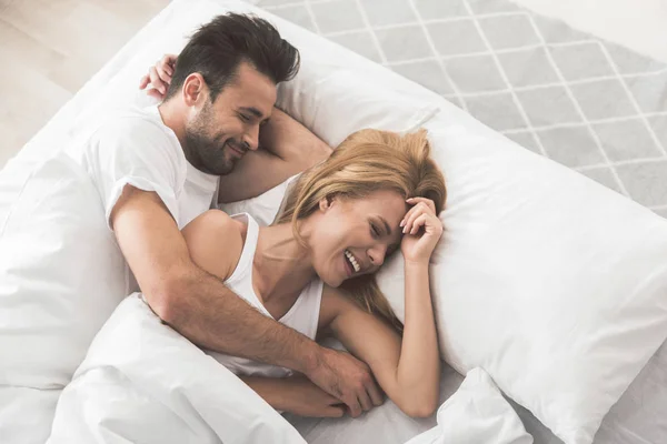 Glada älskare med nap om bekväma sängar — Stockfoto