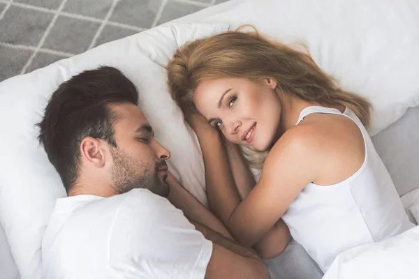 Милая молодая женщина лежит на кровати рядом со своим мужем — стоковое фото