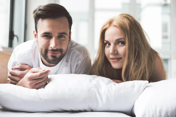 Glad man och kvinna som kopplar på sängkläder — Stockfoto