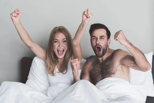 Возбужденная пара празднует победу своей команды в спальне — стоковое фото