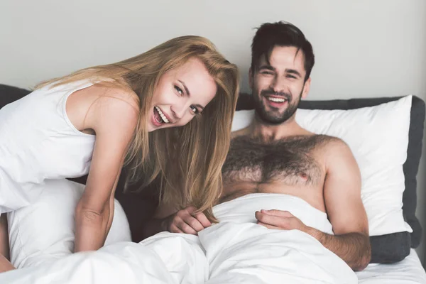 Upphetsad ung man och kvinna som spelar på säng — Stockfoto