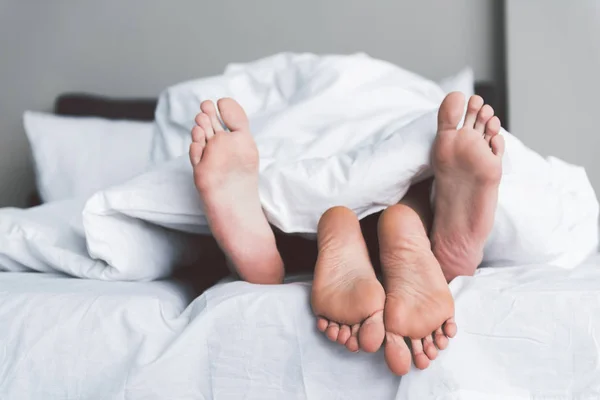 Jonge man en vrouw plezier onder dekbed in slaapkamer — Stockfoto