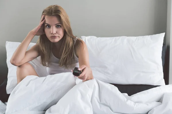 Traurige junge Frau sitzt gelangweilt im Bett — Stockfoto