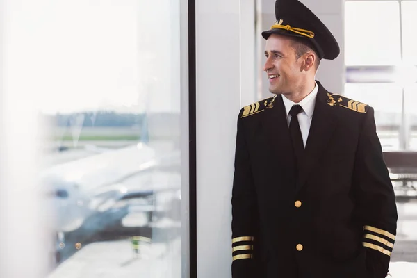 Wesoły, uśmiechnięty pilota stojąc w terminalu — Zdjęcie stockowe
