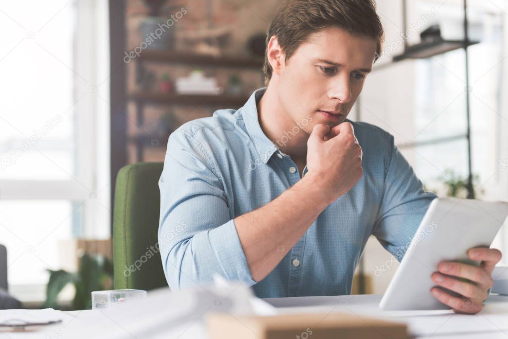 Pleasant attractive youthful man is using modern device