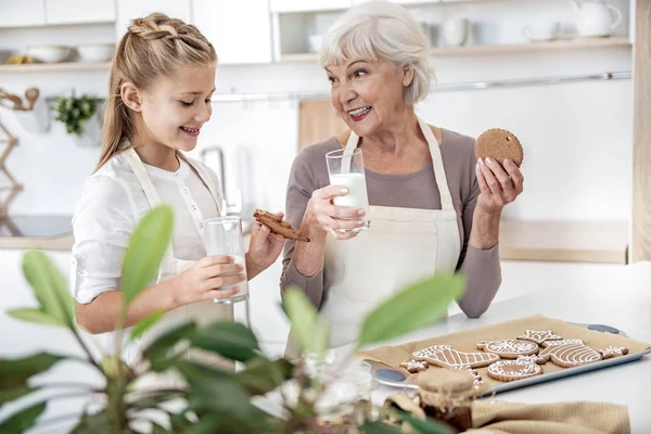 Aufgeregtes Kind probiert selbst gebackene Plätzchen mit Oma — Stockfoto