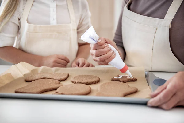 Skillful female arms decorating self-made cookies — Stock Photo, Image