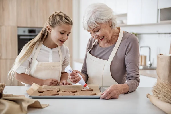 Chica alegre fiesta de hornear comida dulce con la abuela —  Fotos de Stock