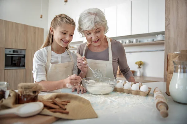 Feliz abuela y chica mezclando comida con huevo en un tazón —  Fotos de Stock