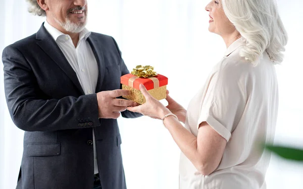 Счастливый старший муж вручает подарок своей жене — стоковое фото