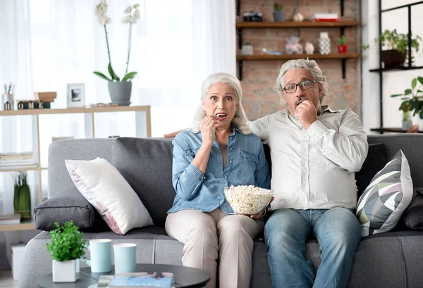 Мужчина и женщина старшего возраста смотрят телевизор дома — стоковое фото