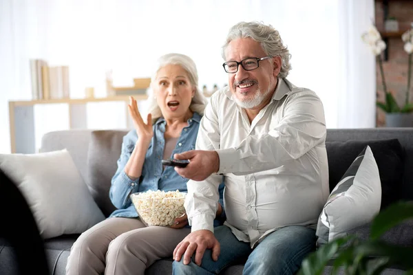 Munter, modent ektepar som ser på TV sammen – stockfoto