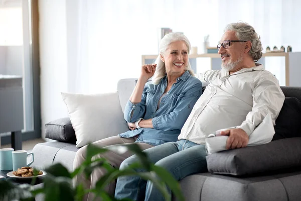 Lystig modent par som ser på TV i leiligheten – stockfoto