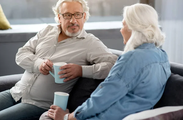 Lykkelig modent par som drikker kaffe sammen hjemme – stockfoto