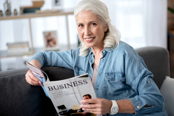 Mulher madura alegre está interessada em notícias de negócios — Fotografia de Stock