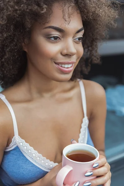 Усміхнена жінка п'є чашку чаю — стокове фото