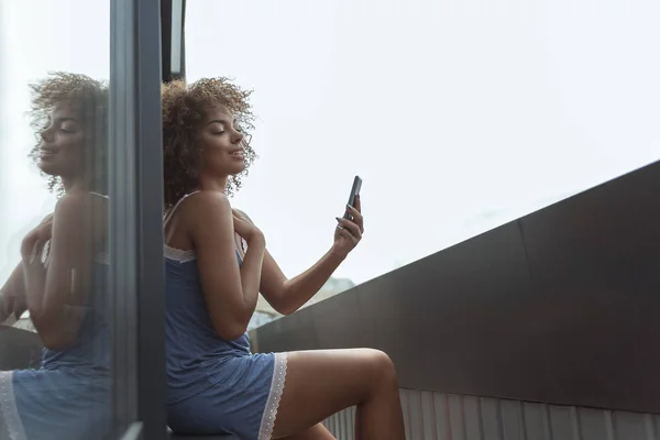 Sorridente donna guardando al cellulare al mattino — Foto Stock