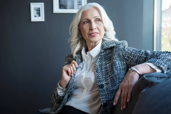 Charming positive senior woman is relaxing on sofa — Stock Photo, Image