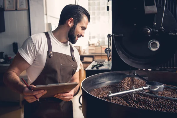 Cheerful glad man writing about roasting beans — Stock Photo, Image