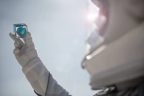 Космонавт держит маленькую стеклянную игрушку — стоковое фото