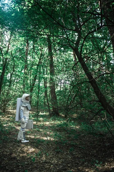 Космонавт в белых доспехах смотрит на дерево — стоковое фото