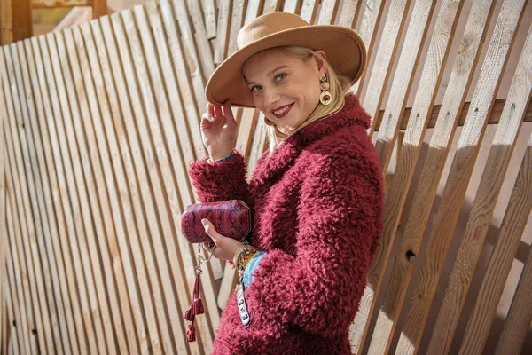 Cheerful blond lady standing near wooden palisade — Stock Photo, Image