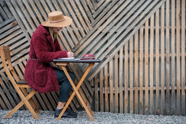 Joyful young woman making notes in writing-pad — Stock Photo, Image