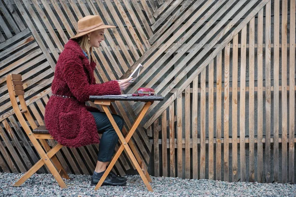 Ahşap çit yakınındaki masada oturan sarışın Bayan