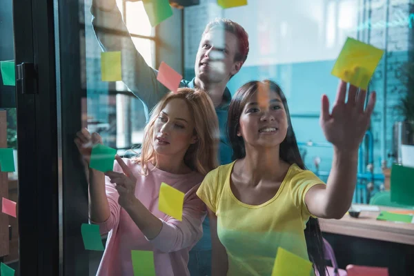 Счастливые коллеги маркируют стикеры на окне — стоковое фото