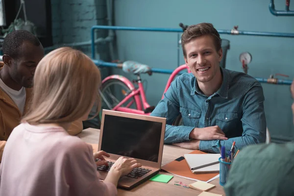 Sonriente hombre situando cerca de colegas en el escritorio — Foto de Stock