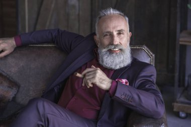 Tıraşsız gülümseyen emekli adam tütün tutmak