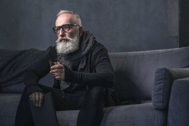 Ciddi emekli kanepede lezzetli içecek tatma