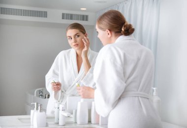 Nemlendirici yüzünü uygulayarak sakin genç kadın