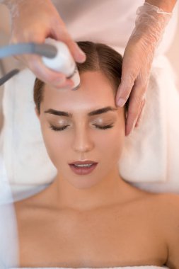 Özel aygıt tarafından cilt tedavisi gören güzellik uzmanı