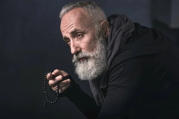 Thoughtful old man holding beads in arm — Stock Photo, Image