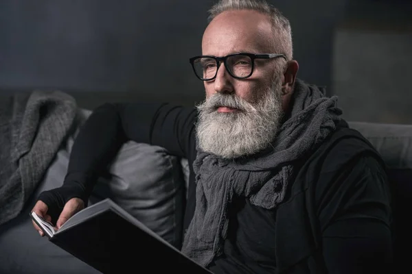 Viejo pensativo mirando a través del volumen — Foto de Stock