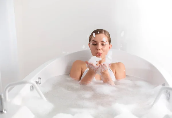 Fröhliche junge Frau bläst Blasen in Badewanne — Stockfoto