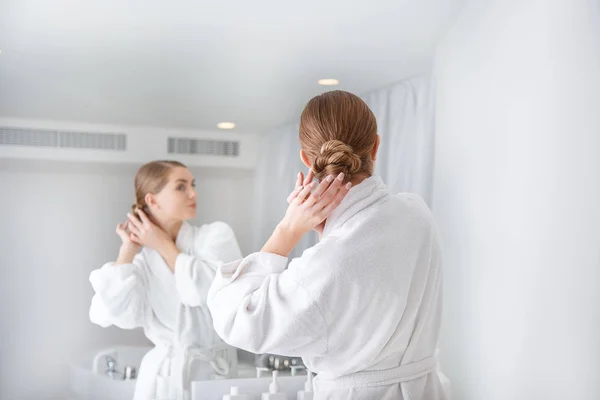 Mujer joven pensativa ajustando su cabello antes de tomar una ducha — Foto de Stock