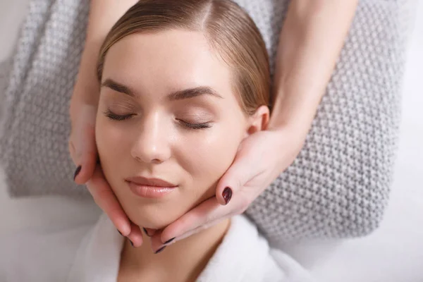 Mujer joven serena recibiendo masaje facial en el spa —  Fotos de Stock