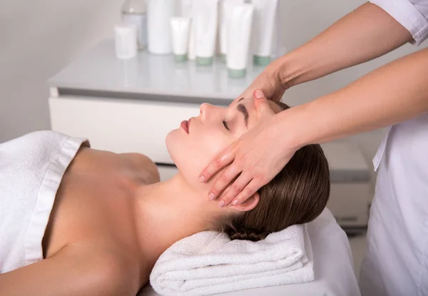 Esteticista hábil massagear rosto feminino — Fotografia de Stock