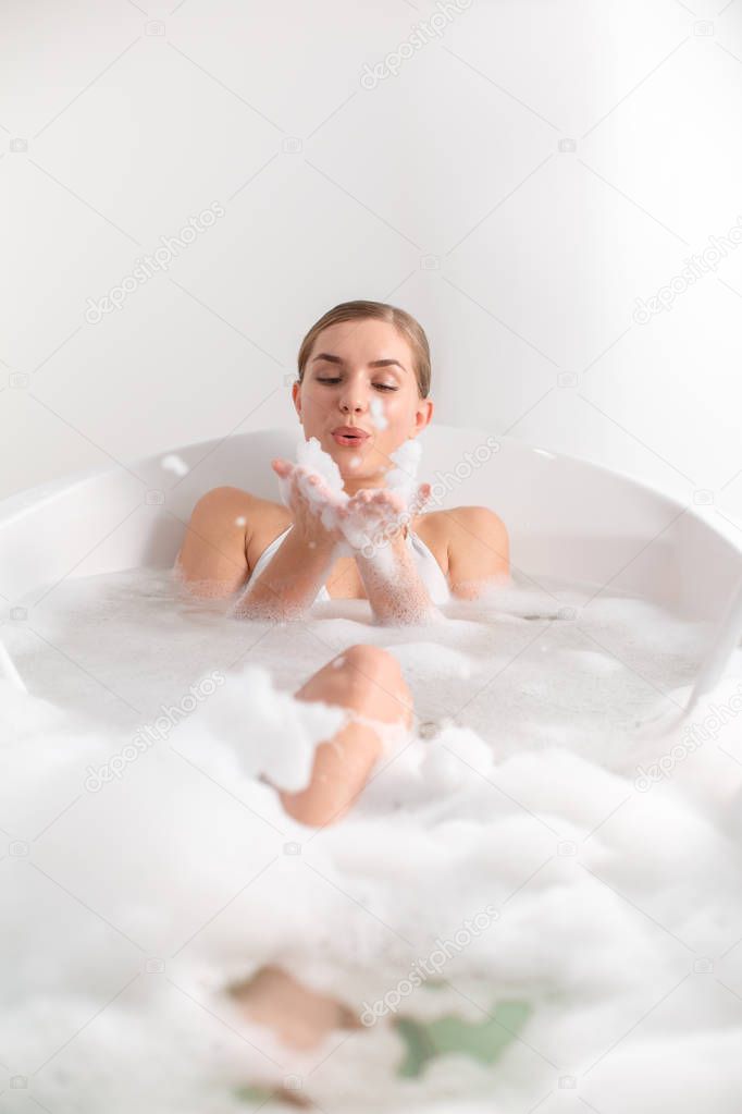 Carefree girl playing with bubbles in bath