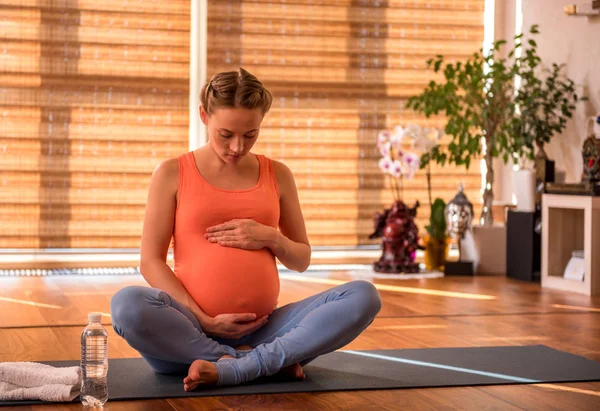 Thoughtful impregnate woman sitting on yoga carpet — Stock Photo, Image