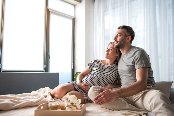 Dreamful zwangere vrouw ontspannen op beddengoed met haar man — Stockfoto
