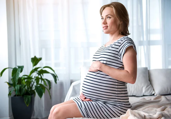 Vidám terhes nő megérintette a hasára ágyon — Stock Fotó