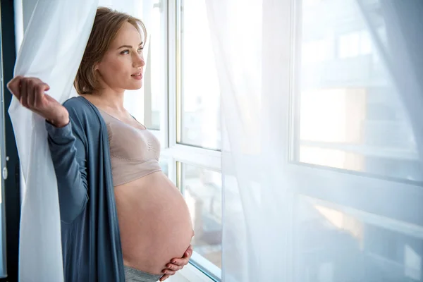 リラックスした妊娠中の母親の窓の近くの夢 — ストック写真