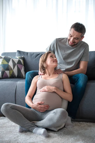 Homem feliz fazendo massagem para a mãe expectante em casa — Fotografia de Stock