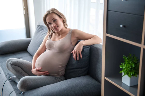 Весела вагітна жінка розслабляється вдома — стокове фото