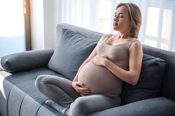 Pacifico grávida mãe relaxante no sofá — Fotografia de Stock